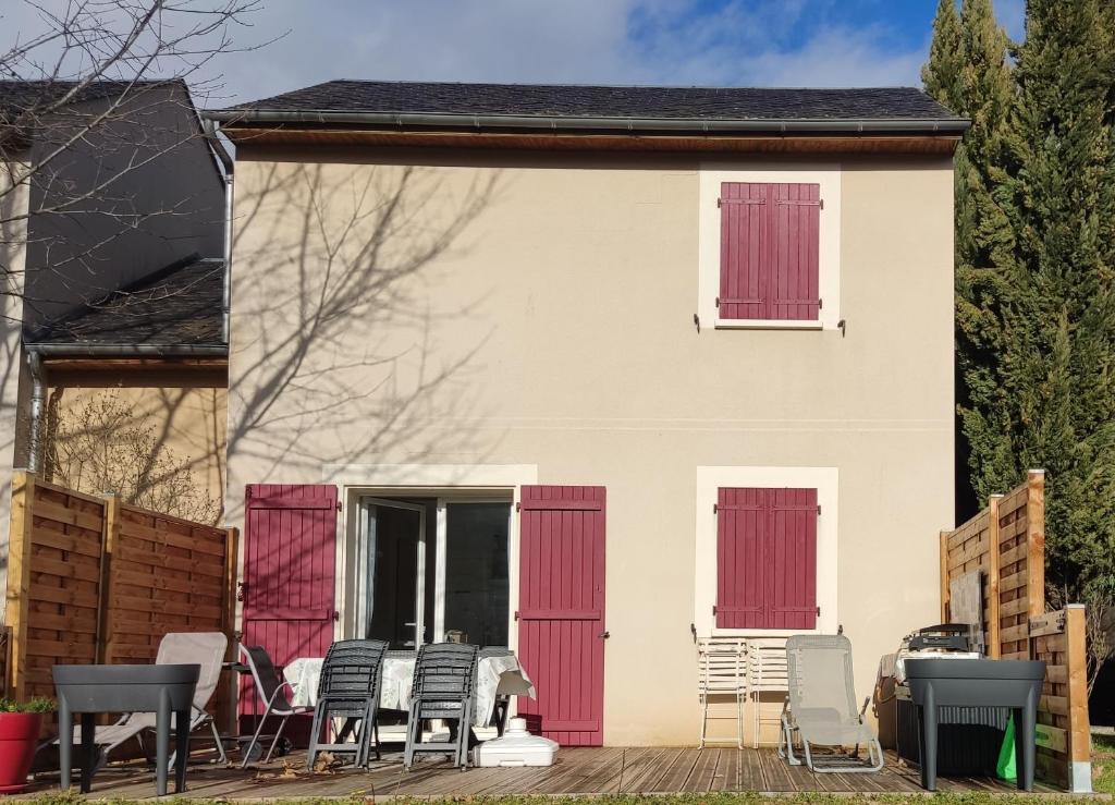 une maison avec des portes rouges et des chaises sur une terrasse dans l'établissement Maison a louer dans village de vacances, à Pierrefiche