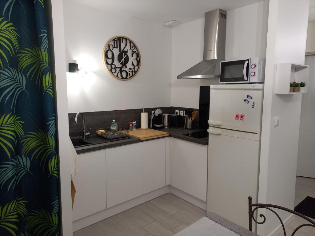 a kitchen with a refrigerator and a clock on the wall at C La Belle Vie in Pessac