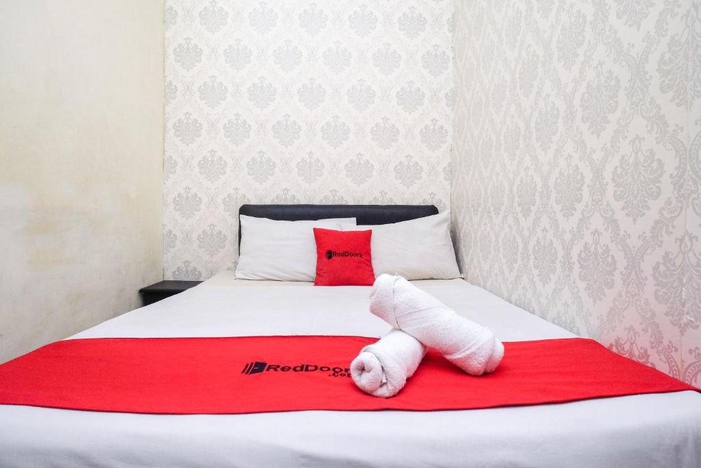 RedDoorz at Mamagayo Inn Yogyakarta في يوغياكارتا: غرفة نوم بسرير وبطانية حمراء