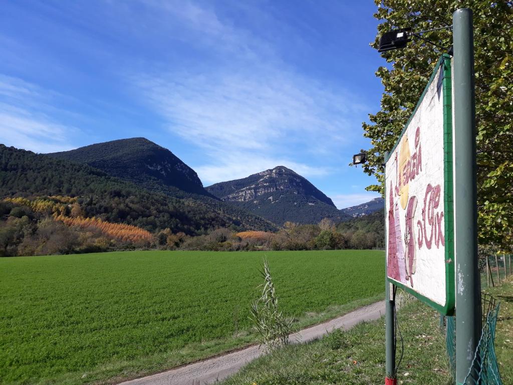 a sign in a field with mountains in the background at Càmping - Bungalows La soleia d'Oix in Oix