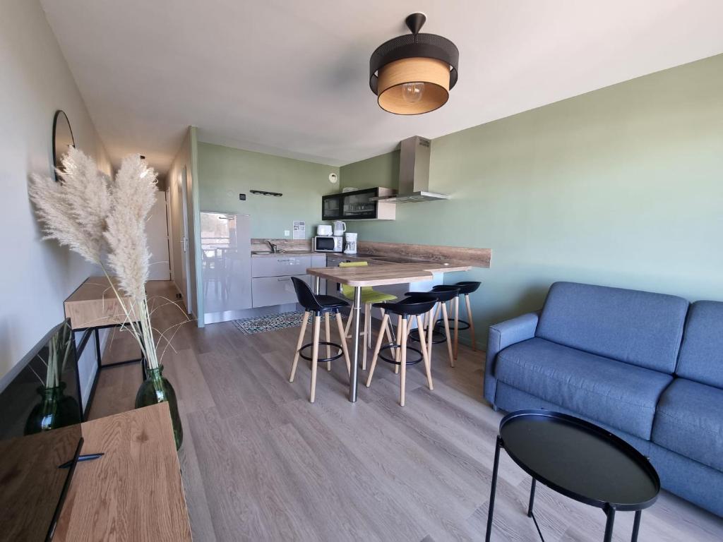 un salon avec un canapé bleu, une table et des chaises dans l'établissement Le Scottish, à Camiers