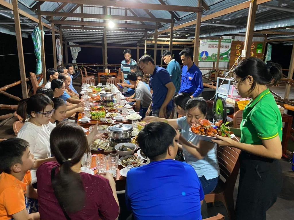 a group of people sitting at tables eating food at Homestay Hải Nam Đất Mũi in Xóm Mũi