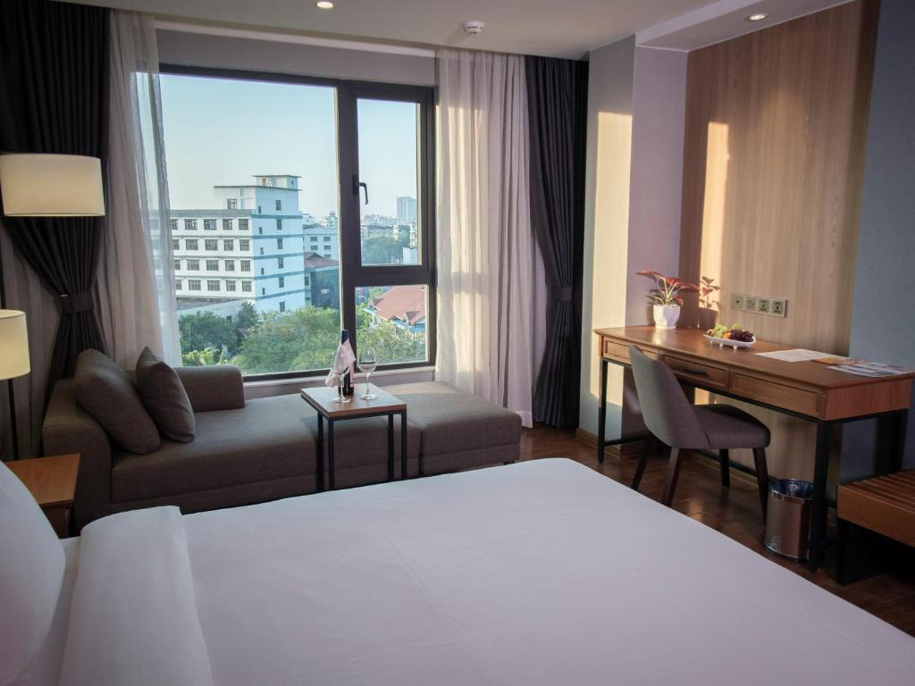 a hotel room with a bed and a desk and a window at Prince Hotel in Yangon