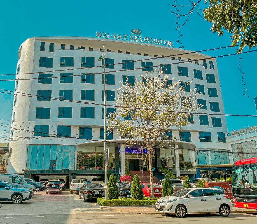 un grande edificio bianco con macchine parcheggiate di fronte di Khách Sạn Hoa Ban Trắng a Sơn La