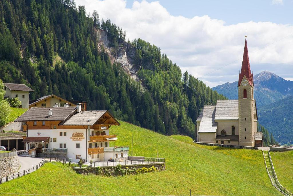 un petit village avec une église sur une colline dans l'établissement Gasthof Trausberg, à Corvara in Passiria