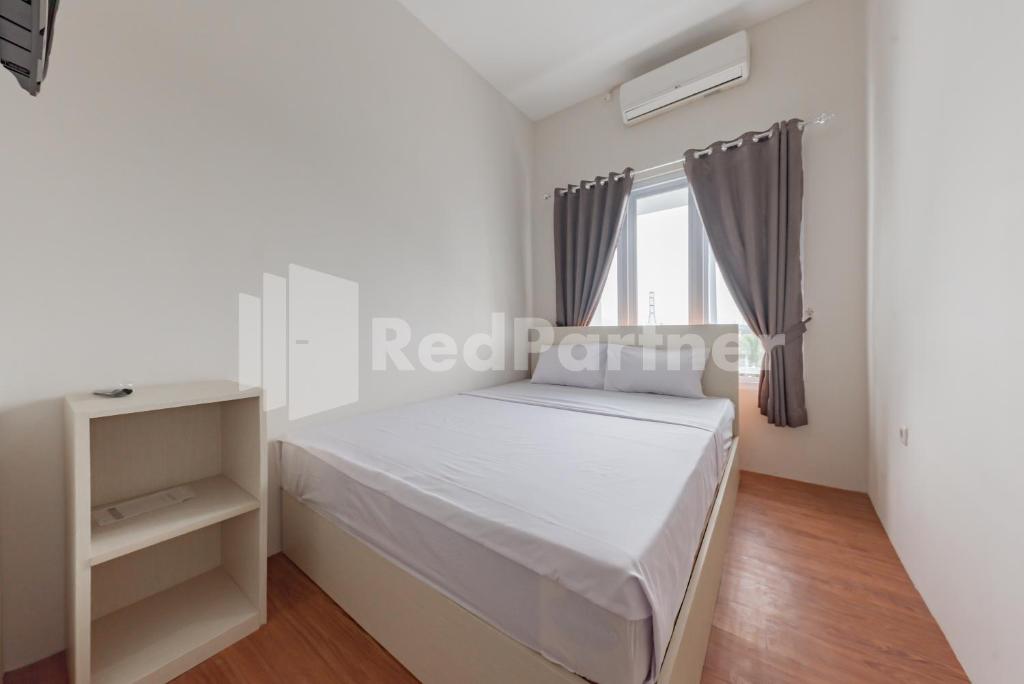 a white bedroom with a bed and a window at 158 Guest House Syariah RedPartner in Bandung
