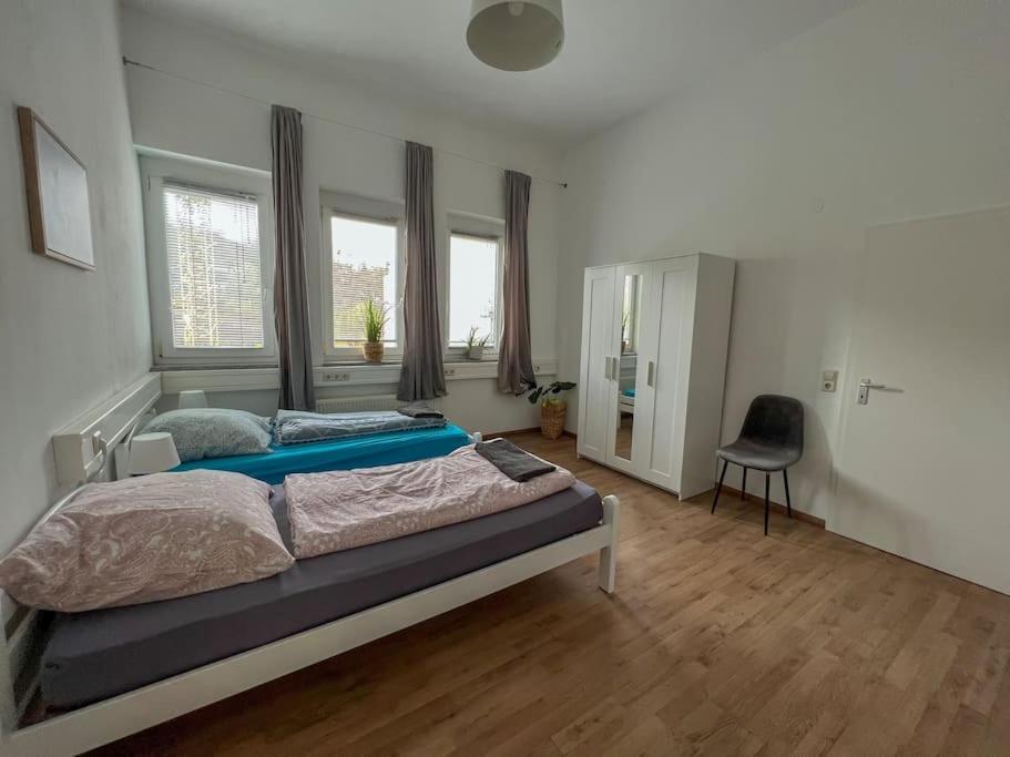 a bedroom with a bed and a chair in it at Modernes Apartment mit Balkon, Parkplatz und Smart Tv bis zu 10 Personen in Weinstadt