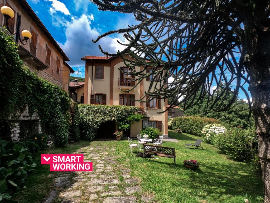 een tuin met een gebouw met een bord waarop staat "slim werken" bij Villa Margherita by Wonderful Italy in Civenna