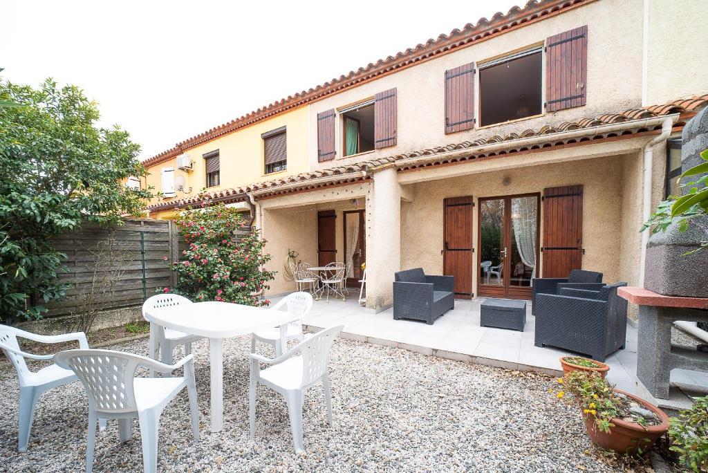 patio z białymi krzesłami i stołem przed domem w obiekcie Chez Colette - Maison proche plage pour 8 w Argelès-sur-Mer