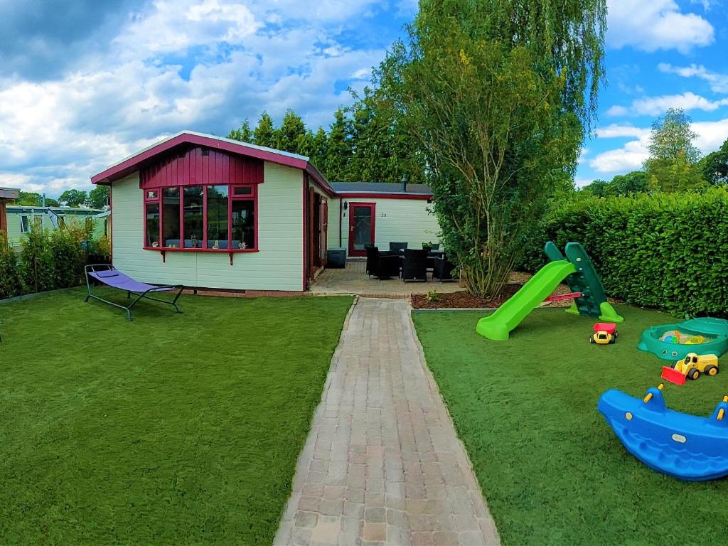 a backyard with a house and a playground at [Veluwe] Chalet De Rode Vos, 2-6p 60m2! Gezinspark! in Voorthuizen