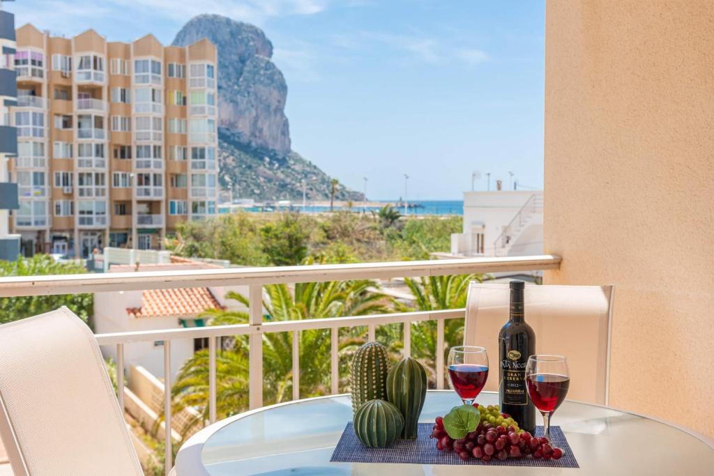 uma mesa com dois copos de vinho numa varanda em Apartamento Arenal 5 - PlusHolidays em Calpe