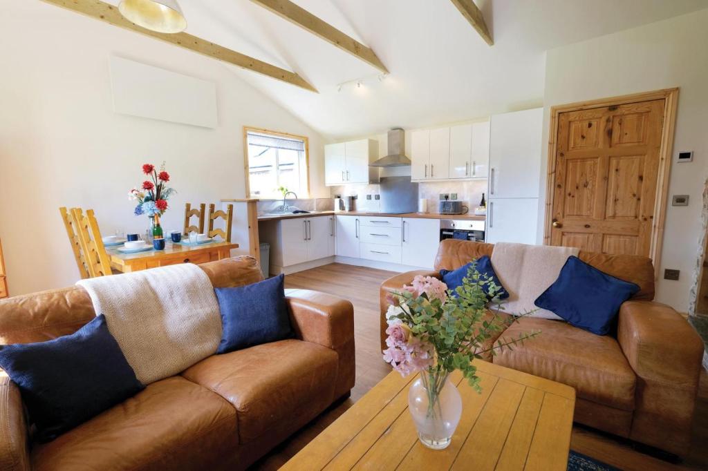 a living room with two couches and a table and a kitchen at Pen Dragon - 2 Bedroom Cottage - Pen-Clawdd in Gowerton