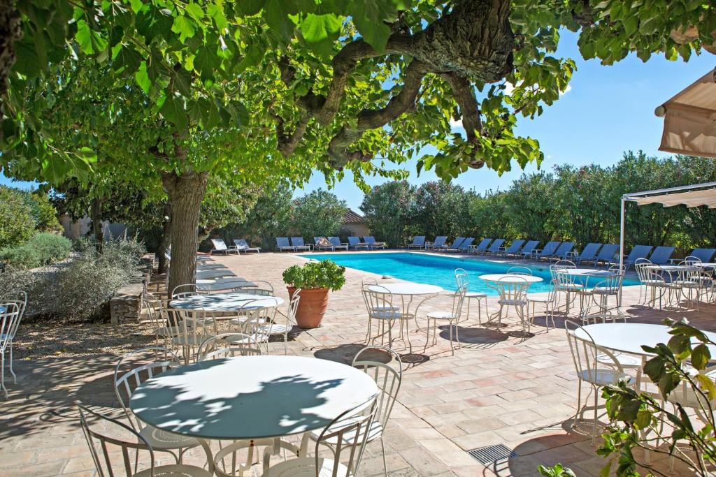un grupo de mesas y sillas junto a una piscina en Hôtel la Figuière en Saint-Tropez