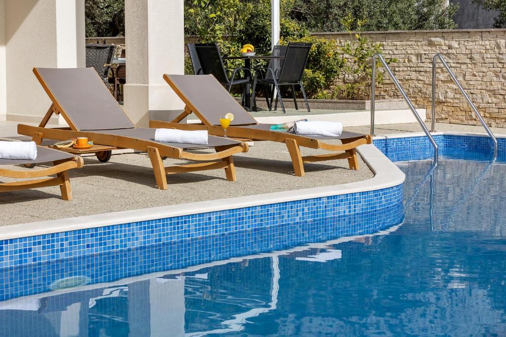 two lounge chairs sitting next to a swimming pool at Apartments Lujnovic in Makarska