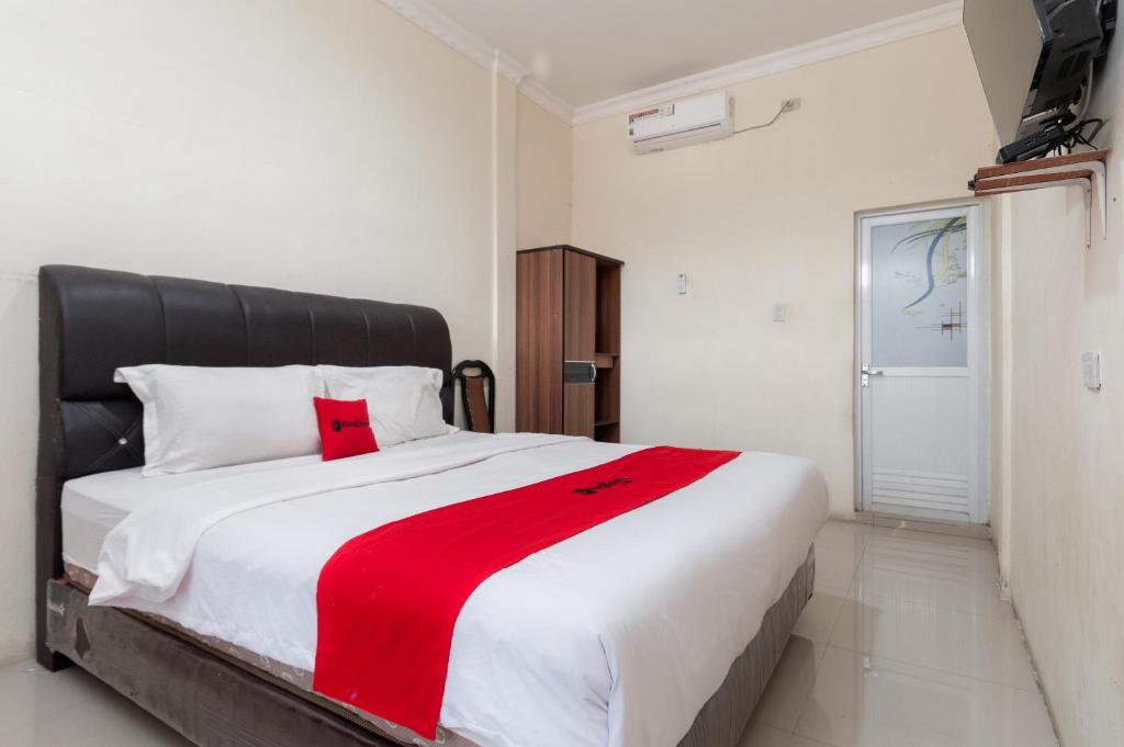a bedroom with a large bed with a red blanket on it at RedDoorz at Samuel Homestay Pematangsiantar in Pematangsiantar