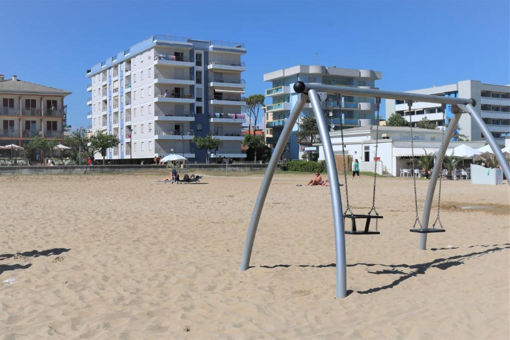an empty swing set in the sand on the beach at Condominio ADRIATICO in Bibione