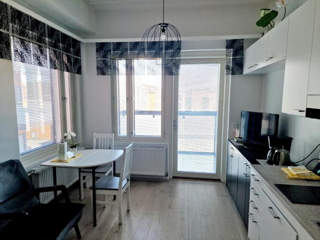 a kitchen with a table and chairs and a room with windows at New Center Sity Home in Kuopio
