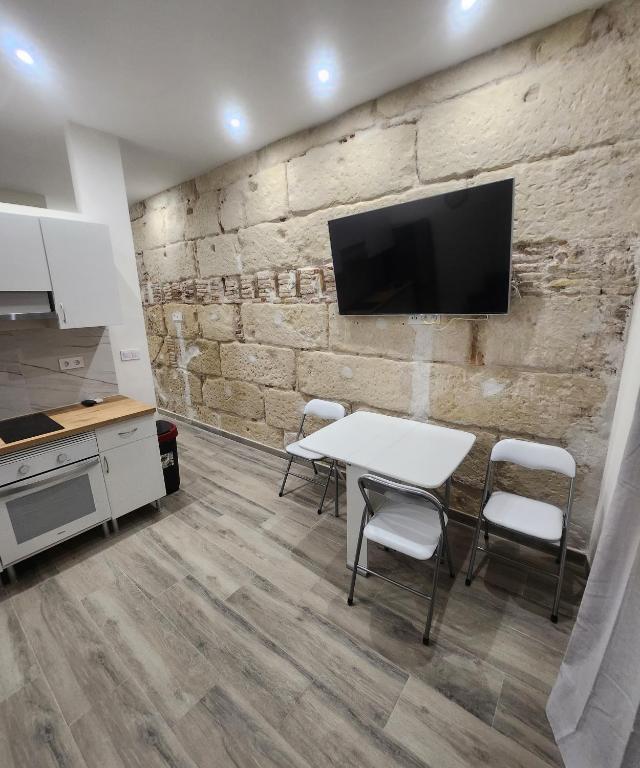 um quarto com uma mesa e cadeiras e uma televisão numa parede de pedra em Green Apartamentos Cartagena em Cartagena
