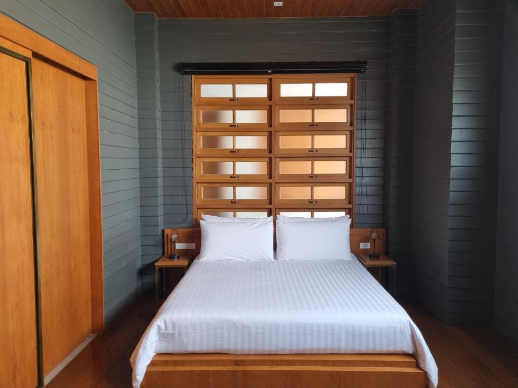 a bedroom with a bed with white sheets and a window at Vali Villa Bangkok in Bangkok