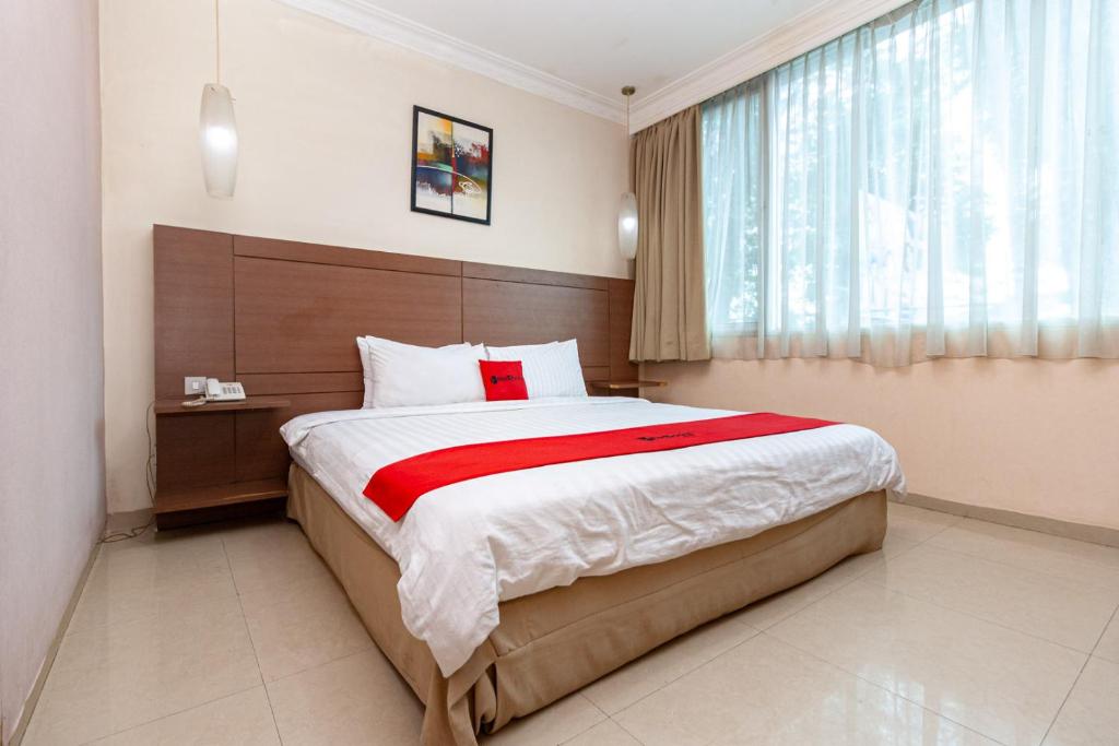 RedDoorz Premium at Hotel Ratu Residence في Palmerah: غرفة نوم بسرير كبير ونافذة
