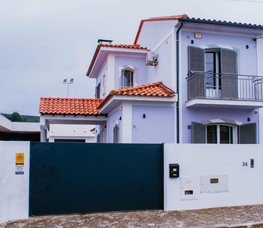 ein weißes Haus mit einem grünen Zaun davor in der Unterkunft Bird’s Home in Aveiro
