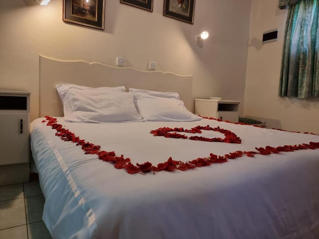 a bed with a red rose decoration on it at Neat standard room in guesthouse - 2088 in Bulawayo
