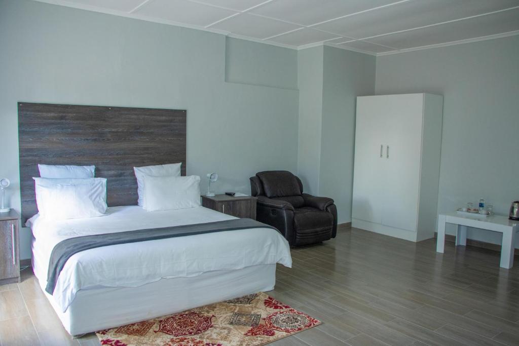 - une chambre avec un grand lit blanc et une chaise dans l'établissement Neat one bedroom in Morningside guesthouse - 2089, à Bulawayo
