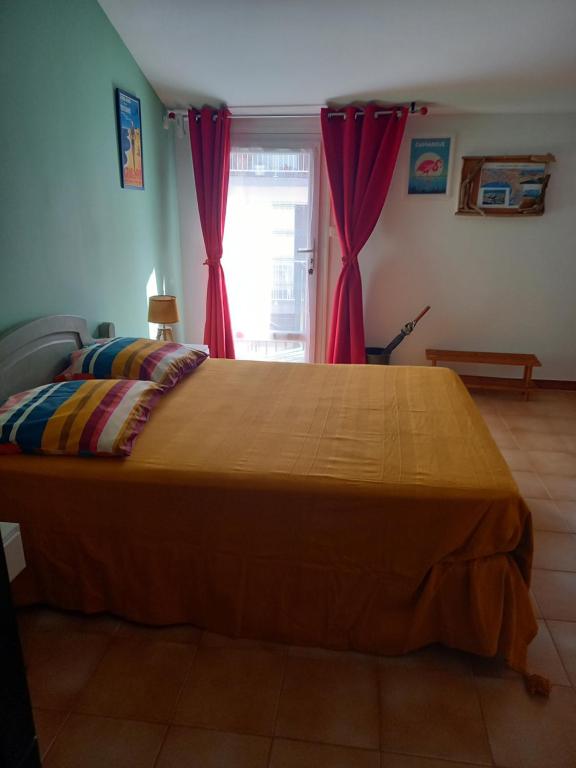 - une chambre avec un grand lit et des rideaux rouges dans l'établissement Studio Grau du Roi avec jardin, au Grau-du-Roi