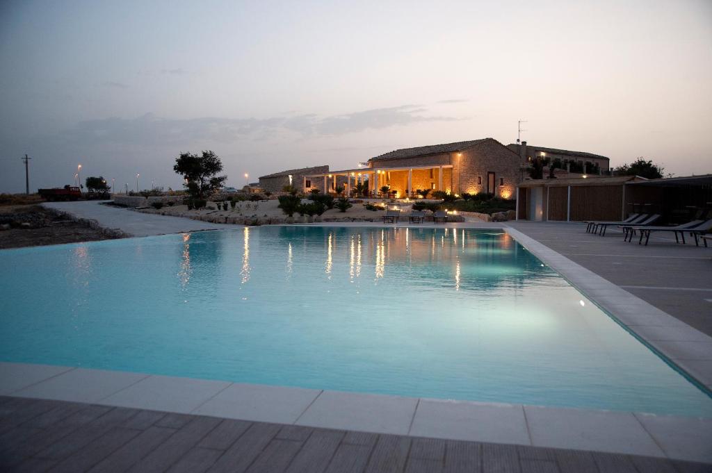 una piscina por la noche con una casa en el fondo en La Dimora di Spartivento - BW Signature Collection, en Ragusa