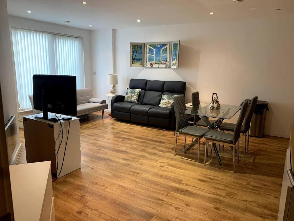 a living room with a black couch and a glass table at Large Private Flat in City Centre Leeds in Leeds