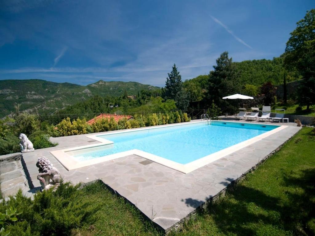 una piscina en un patio con una montaña en el fondo en Villa with pool in chianti Rufina area (19 sleeps) with cooking class included en San Godenzo