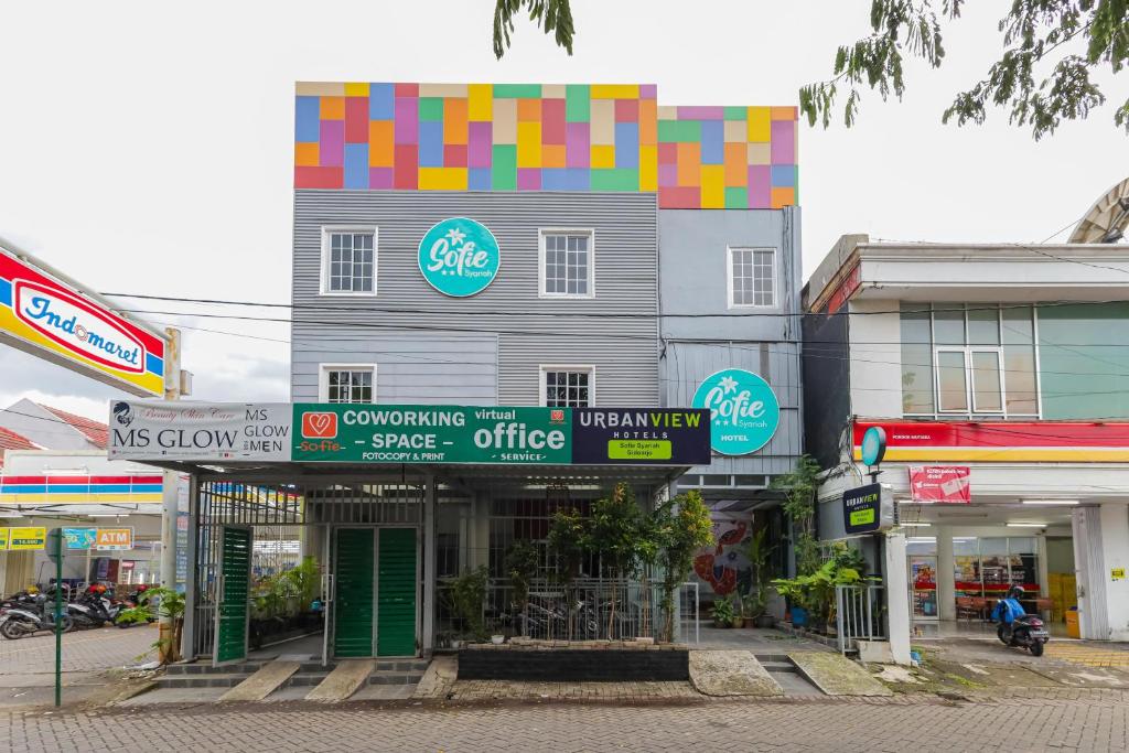 a building with colorful signs on it on a street at Urbanview Hotel Syariah Near Gelora Delta Sidoarjo in Sidoarjo