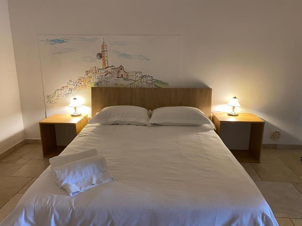 een slaapkamer met een groot wit bed met 2 lampen bij La Luna nei Sassi in Matera