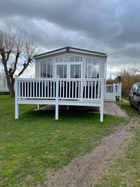 une maison blanche avec une véranda et une voiture dans l'établissement ParkDean cherry tree holiday park, à Great Yarmouth