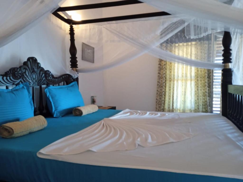 1 dormitorio con cama con dosel y almohadas azules en Pearl Cave Cabanas & Resturant, en Tangalle