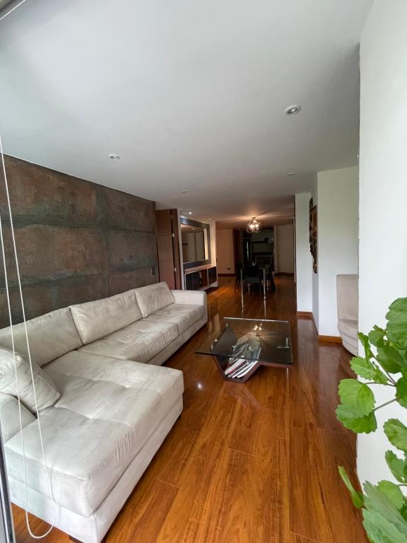 uma sala de estar com um sofá branco e uma mesa em Lujoso Apartamento parque el Virrey em Bogotá