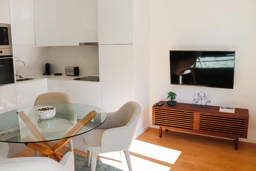 uma cozinha com uma mesa e cadeiras de vidro e uma televisão em Fish Village Terrace Luxo em Vila Nova de Gaia