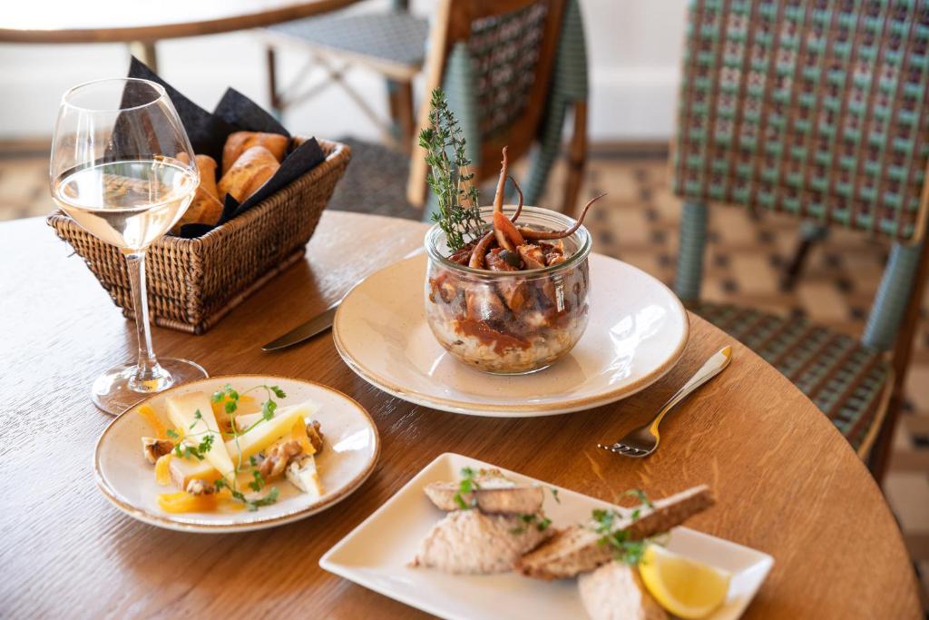 a table with plates of food and a glass of wine at Les Terrasses du Bailli in Rayol-Canadel-sur-Mer