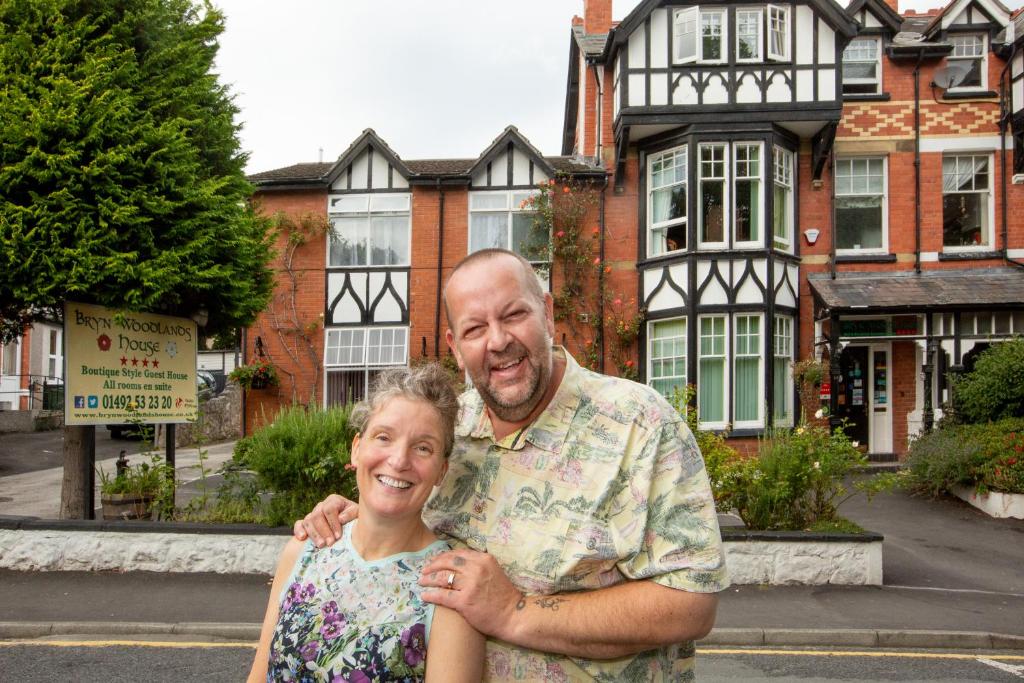 een man en een vrouw die voor een huis staan bij Bryn Woodlands House in Colwyn Bay