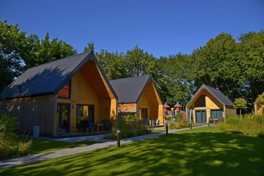 ein Haus mit grünem Rasen davor in der Unterkunft Ośrodek Wypoczynkowy Zapach Drewna Resort & Lake in Barczewo