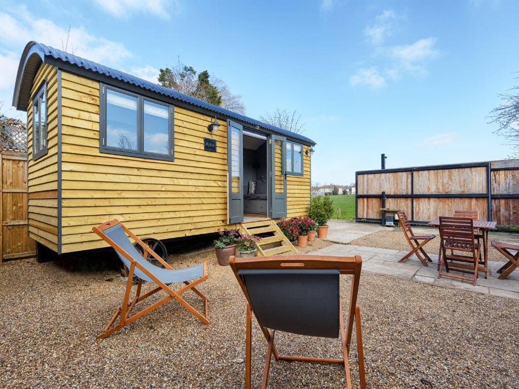 a yellow tiny house with chairs and a table at Pass the Keys Whitstable Shepherds Hut minutes from the Harbour in Whitstable