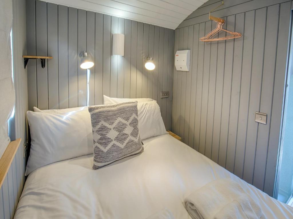a small bedroom with a bed with white pillows at Pass the Keys Whitstable Shepherds Hut minutes from the Harbour in Whitstable