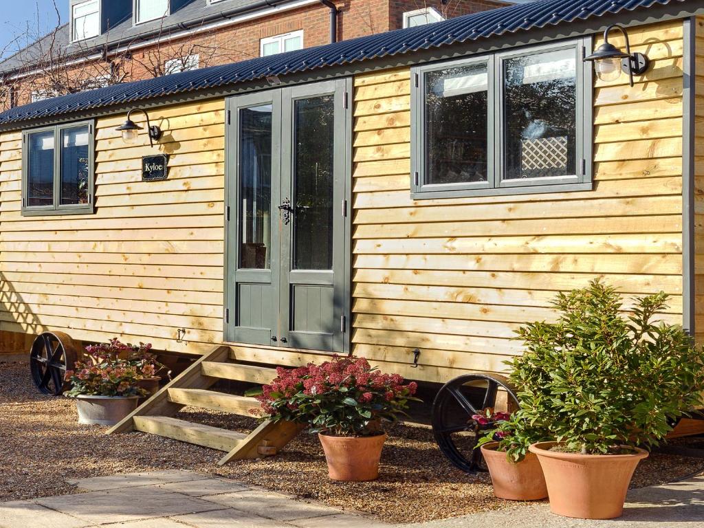 a wooden house with a porch and some plants at Pass the Keys Whitstable Shepherds Hut minutes from the Harbour in Whitstable