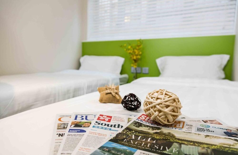 a room with two beds with a newspaper and a cat toy at Pop E INN-B&B in Hong Kong