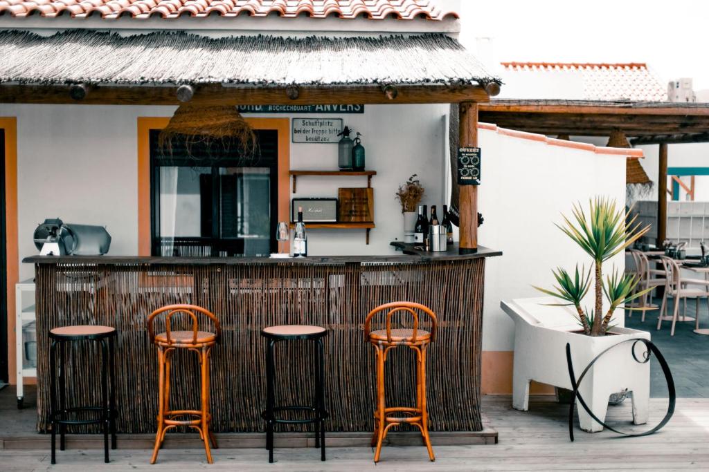 a bar with orange stools in front of a building at Casa Idalia Boutique Hotel in Comporta