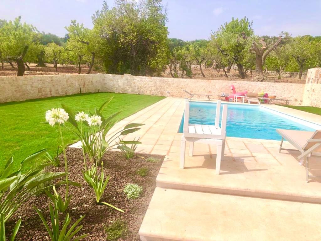 una piscina con un banco junto a un patio en Trulli di Pone, en Cozzana