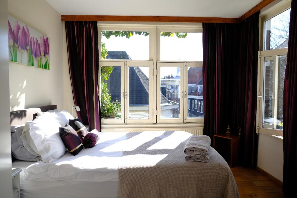 een slaapkamer met een bed en een groot raam bij Studio Eelhouse in Amsterdam