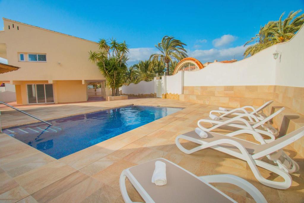 a pool with lounge chairs next to a building at Villa Corina - Plusholidays in Calpe