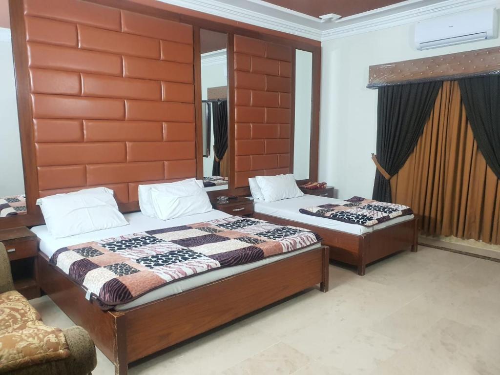 a bedroom with two beds and a chair at Defence Guest House in Karachi