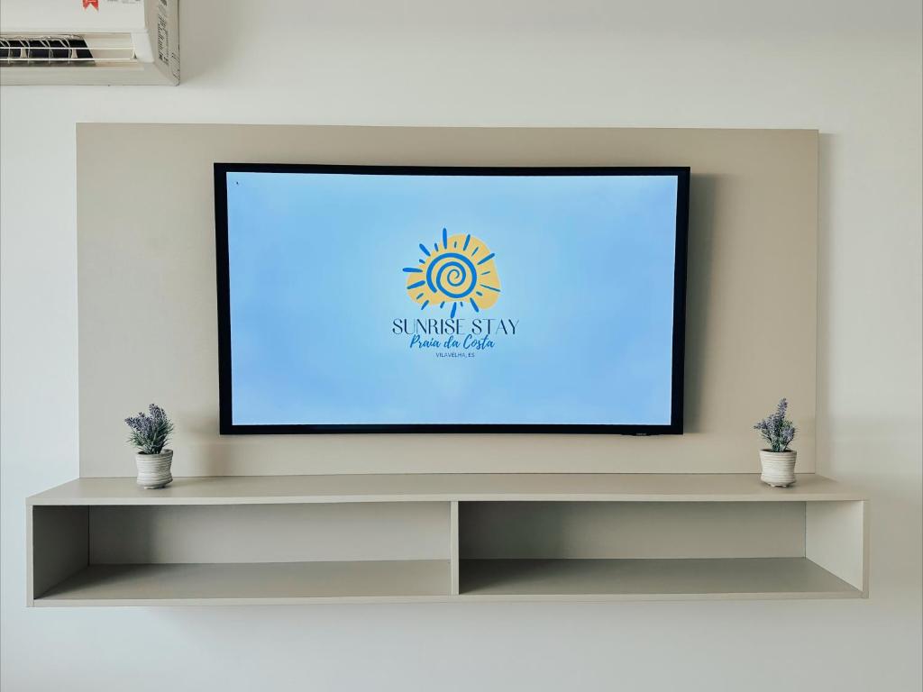a flat screen tv sitting on top of a shelf at Praia da Costa, SUNRISE STAY in Vila Velha